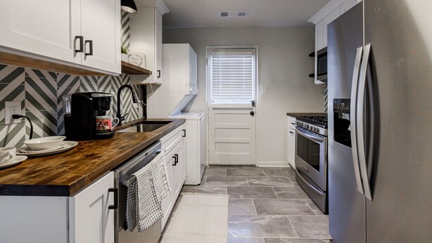 A modern kitchen with white cabinets, a wooden countertop, a stainless steel refrigerator, and a built-in oven. - 5min-Grant park|Fenced Yard|Parking|Fire Pit&BBQ (Atlanta)