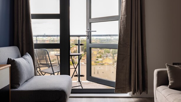 A room with a balcony, a sofa, a chair, and a table. - Beautiful Canal-Side Apartment in Islington (London)