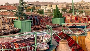 A rooftop with a variety of colorful textiles and a large blue hot air balloon labeled "ATMOM BALLOO" in the background. - Underground Cave Suites (Avanos)