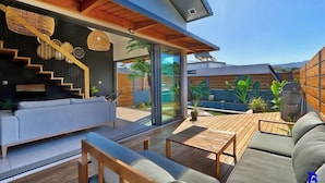 Un'area esterna moderna con un patio in legno, una panca integrata e una scala che conduce a un livello superiore.