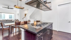 Eine moderne Küche mit Kochinsel, Edelstahlgeräten und einem Essbereich mit Holztischen und -stühlen.