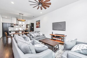 A modern living room with a grey sofa set, a wooden coffee table, and a mounted TV. - EaDo w/ Rooftop Bar | City Views | Private Jacuzzi (Houston)