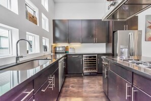 Una cocina moderna con armarios oscuros, electrodomésticos de acero inoxidable y un horno empotrado.