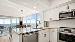 A modern kitchen with white cabinets, stainless steel appliances, a large window, and a view of the ocean. - Rent the best! Oceanfront! Gorgeous remodel! 3 bedrooms 3 baths! Views! Views! (Myrtle Beach)