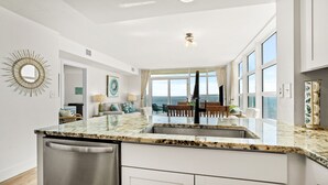 A modern kitchen with a large island, white cabinetry, and a view of the ocean. - Rent the best! Oceanfront! Gorgeous remodel! 3 bedrooms 3 baths! Views! Views! (Myrtle Beach)