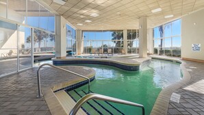 An indoor swimming pool with clear glass walls, a tiled deck, and a sign indicating shallow water and no diving allowed. - Rent the best! Oceanfront! Gorgeous remodel! 3 bedrooms 3 baths! Views! Views! (Myrtle Beach)