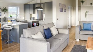 A modern kitchen with a central island, a grey sofa, and a grey armchair in a living area. - 3 bedroom accommodation in Barrow, near Clitheroe (Barrow, near Clitheroe)