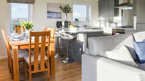 A modern kitchen with a central island, a dining area with wooden chairs, and a grey sofa. - 3 bedroom accommodation in Barrow, near Clitheroe (Barrow, near Clitheroe)