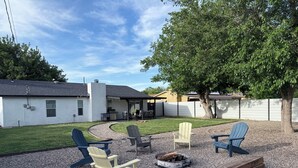 Ein Garten mit Sitzgelegenheit im Freien, Grillplatz und überdachter Terrasse.
