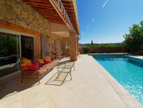 Relax by the serene pool surrounded by a stone wall and patio area, perfect for unwinding with a comfortable seating arrangement.