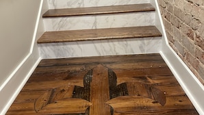 Eine Treppe mit weißen Marmorstufen und Holzhandläufen, die zu einem Holzboden mit geschnitztem Dekor führt.