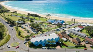 An aerial view of a coastal area with a beach, parking lots, and residential buildings. - Breakers 4 - Bright spacious apartment in the heart of Mollymook (Mollymook)