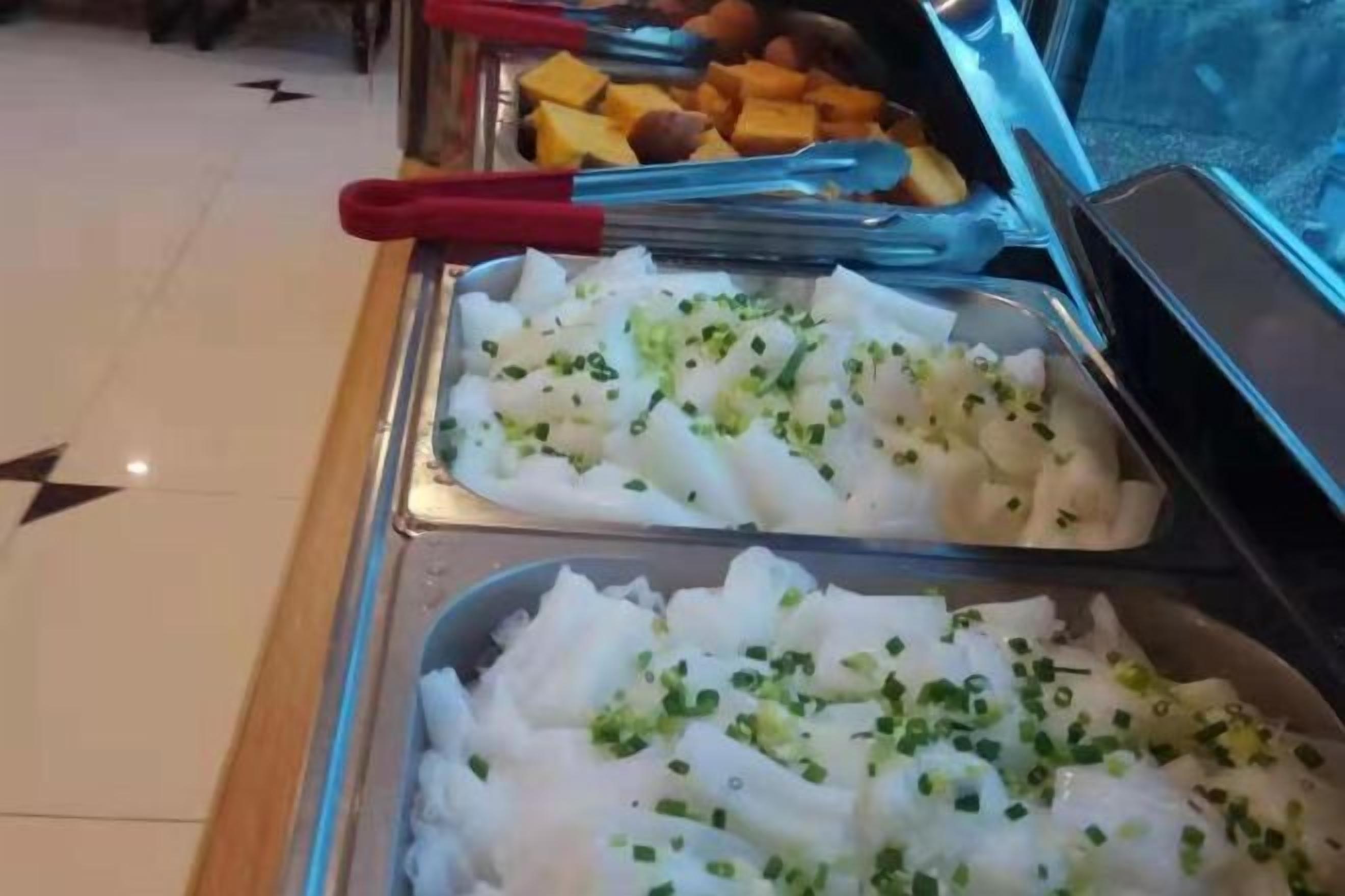 A buffet with various food items, including a tray of white food garnished with green herbs.