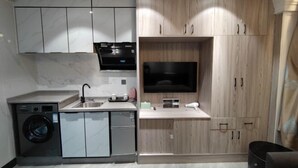 A compact kitchen with a built-in washing machine, a sink, and wooden cabinets. - Haitao Hotel (Zhaoqing Seven Star Rock Archway Scenic Spot) (Zhaoqing)
