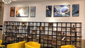A modern interior with a black grid wall unit displaying various items, yellow armchairs, and abstract art on the wall. - Haitao Hotel (Zhaoqing Seven Star Rock Archway Scenic Spot) (Zhaoqing)