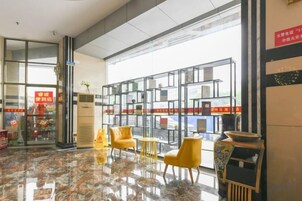 A hotel lobby with a glass partition, seating area, and a vending machine.