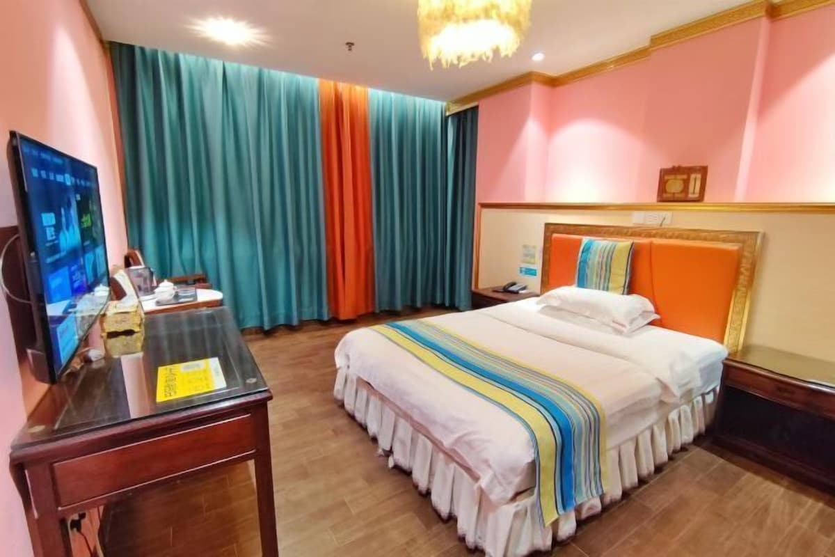 A hotel room with a bed, a desk, a television, and curtains.