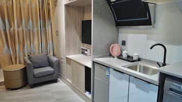 A modern kitchen with a built-in microwave, a sink, and a small seating area with a chair and a side table.