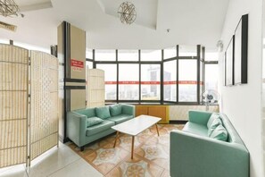A modern living room with a sofa set, a coffee table, and large windows offering a city view.