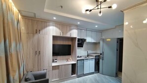 A modern kitchen with built-in appliances, a dining area with a table and chairs, and a television mounted on the wall. - Haitao Hotel (Zhaoqing Seven Star Rock Archway Scenic Spot) (Zhaoqing)