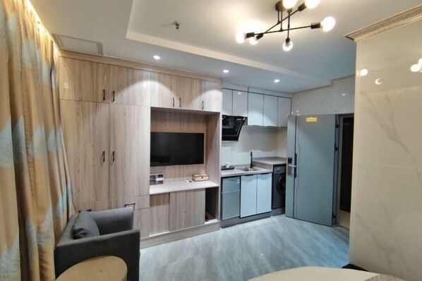 A modern kitchen with built-in appliances, a dining area with a table and chairs, and a television mounted on the wall. - Haitao Hotel (Zhaoqing Seven Star Rock Archway Scenic Spot) (Zhaoqing)