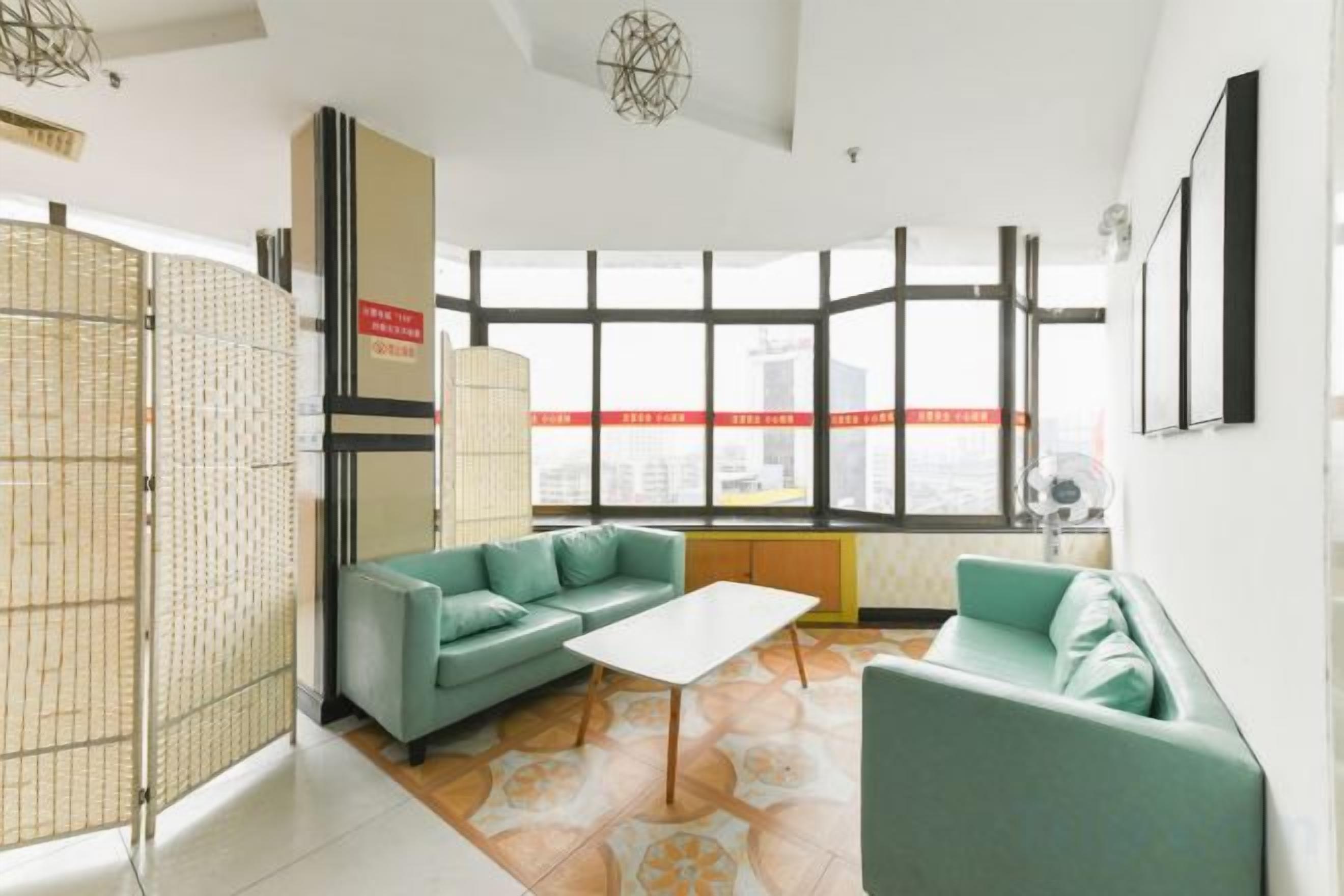 Una sala de estar moderna con un ventanal grande, un sofá, una mesa de centro y un separador decorativo.