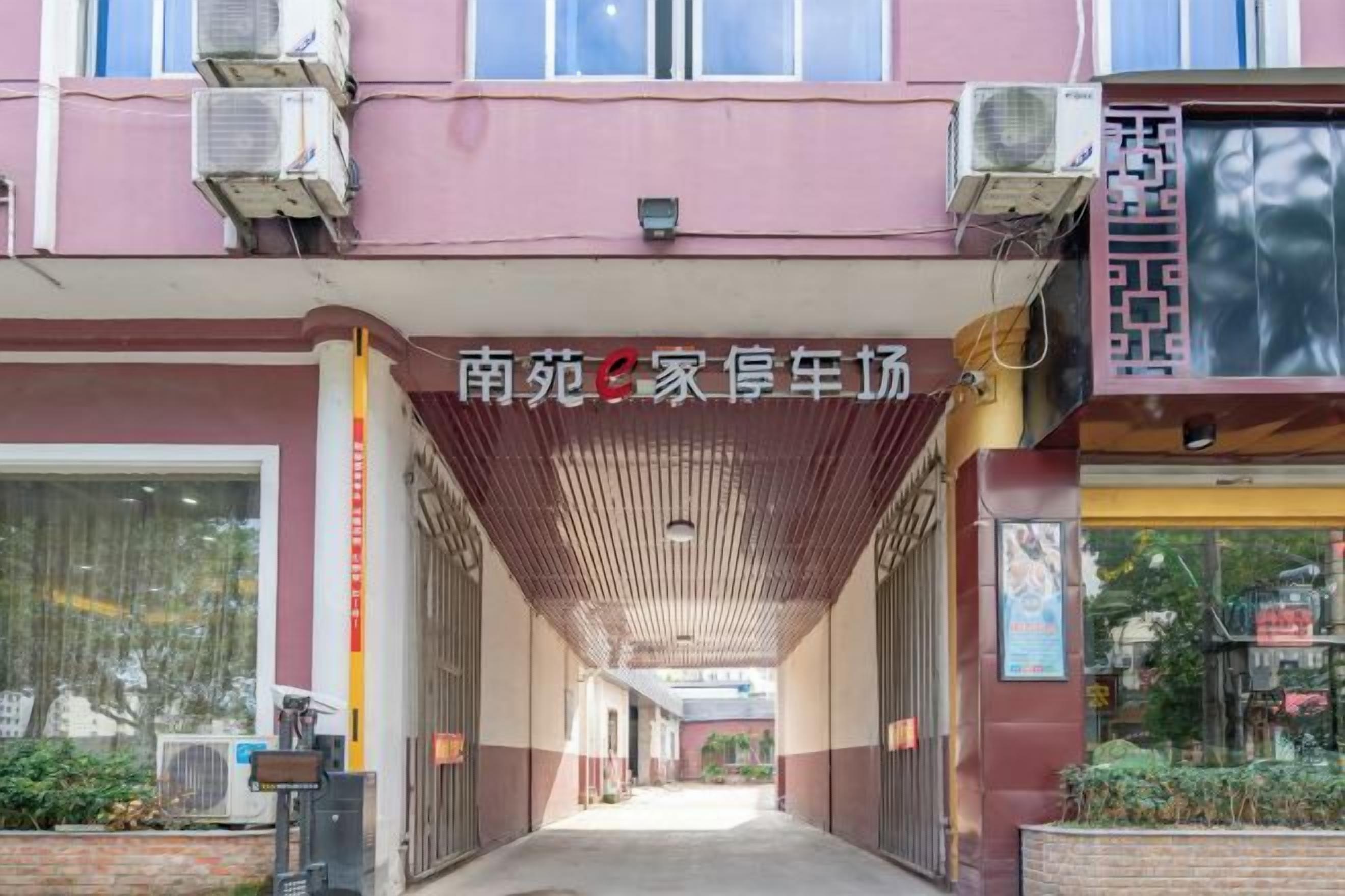 A covered walkway leading to a building with air conditioning units and a signboard.