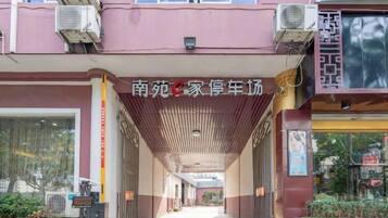 A covered walkway leading to a building with air conditioning units and a signboard.