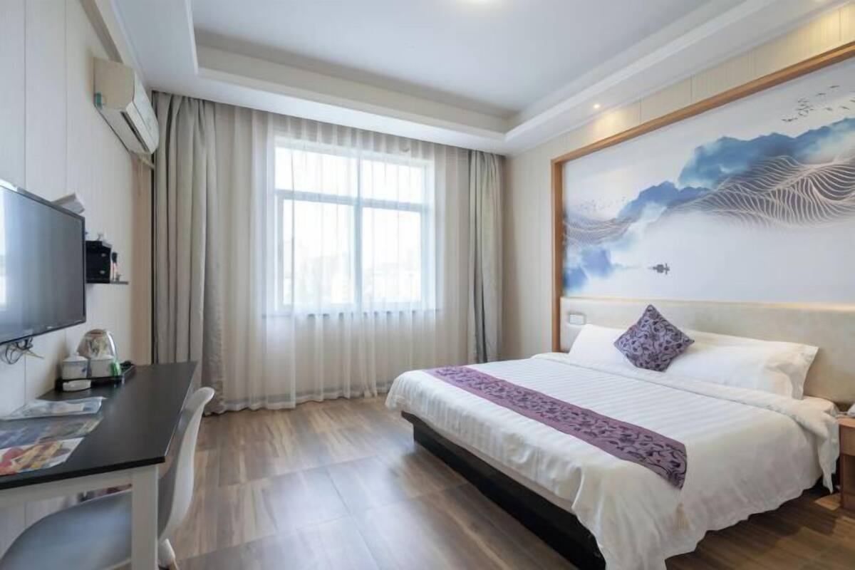 A hotel room with a large bed, a desk with a computer, and a TV.