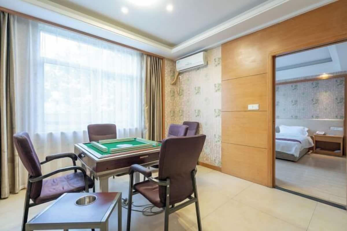 Quarto de hotel com mesa de bilhar, duas cadeiras, uma cama e um banheiro visível através de uma porta aberta.