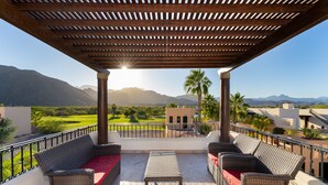 A covered outdoor seating area with wicker furniture and a view of mountains.