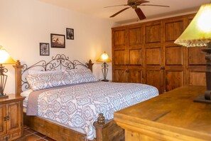 Ein Schlafzimmer mit Bett, Holzschrank, zwei Nachttischlampen und Deckenventilator.