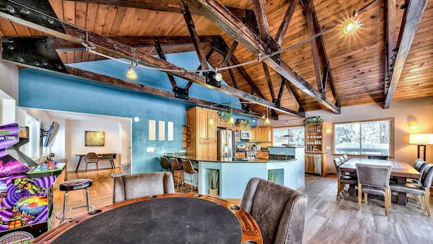 A spacious living area with a high ceiling, wooden beams, a large round table, and comfortable seating.