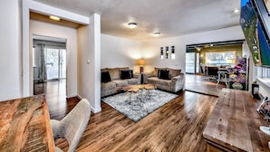 A spacious living area with a wooden floor, two sofas, a coffee table, and a TV.