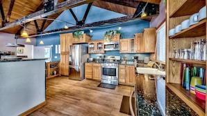 A spacious kitchen with wooden cabinets, stainless steel appliances, and a wooden ceiling.