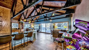 A spacious room with wooden beams, a bar area, and a gaming table featuring a 'Teenage Mutant Ninja Turtles' theme.
