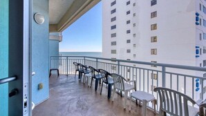 A balcony with chairs and a table, overlooking a high-rise building. - HS-0813 Ocean View 2-Bedroom Condo in Myrtle Beach (Myrtle Beach)