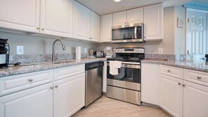 A modern kitchen with white cabinetry, stainless steel appliances, granite countertops, and recessed ceiling lights. - HS-0813 Ocean View 2-Bedroom Condo in Myrtle Beach (Myrtle Beach)