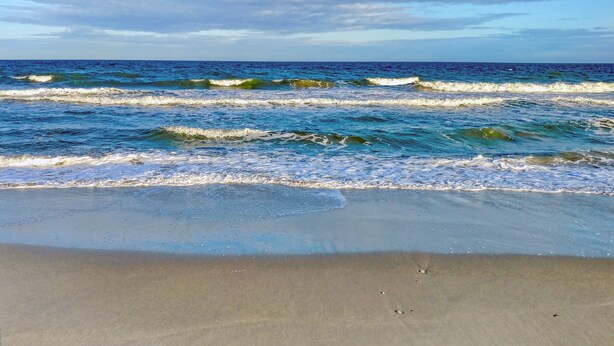 A beach with waves, sand, and a clear sky. - HS-0813 Ocean View 2-Bedroom Condo in Myrtle Beach (Myrtle Beach)