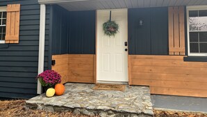 A house with a dark exterior, a white door, and a welcome wreath.