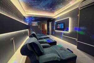 Quarto com cadeiras de massagem, televisão e teto estrelado.