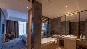 A modern hotel bathroom with a bathtub, a large mirror, and a sink. - Zhanpeng International Hotel (Chongzuo)