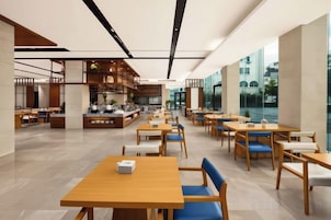 Um restaurante amplo com várias áreas de estar, incluindo mesas e cabines, e um bar central.