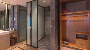 A modern bathroom with a glass shower enclosure, a vanity with a mirror, and a wooden storage unit. - Zhanpeng International Hotel (Chongzuo)