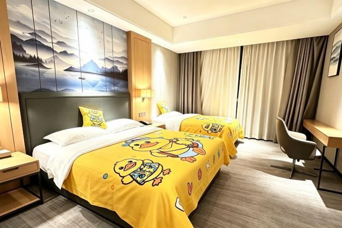 A hotel room with two beds, a desk, and a chair.