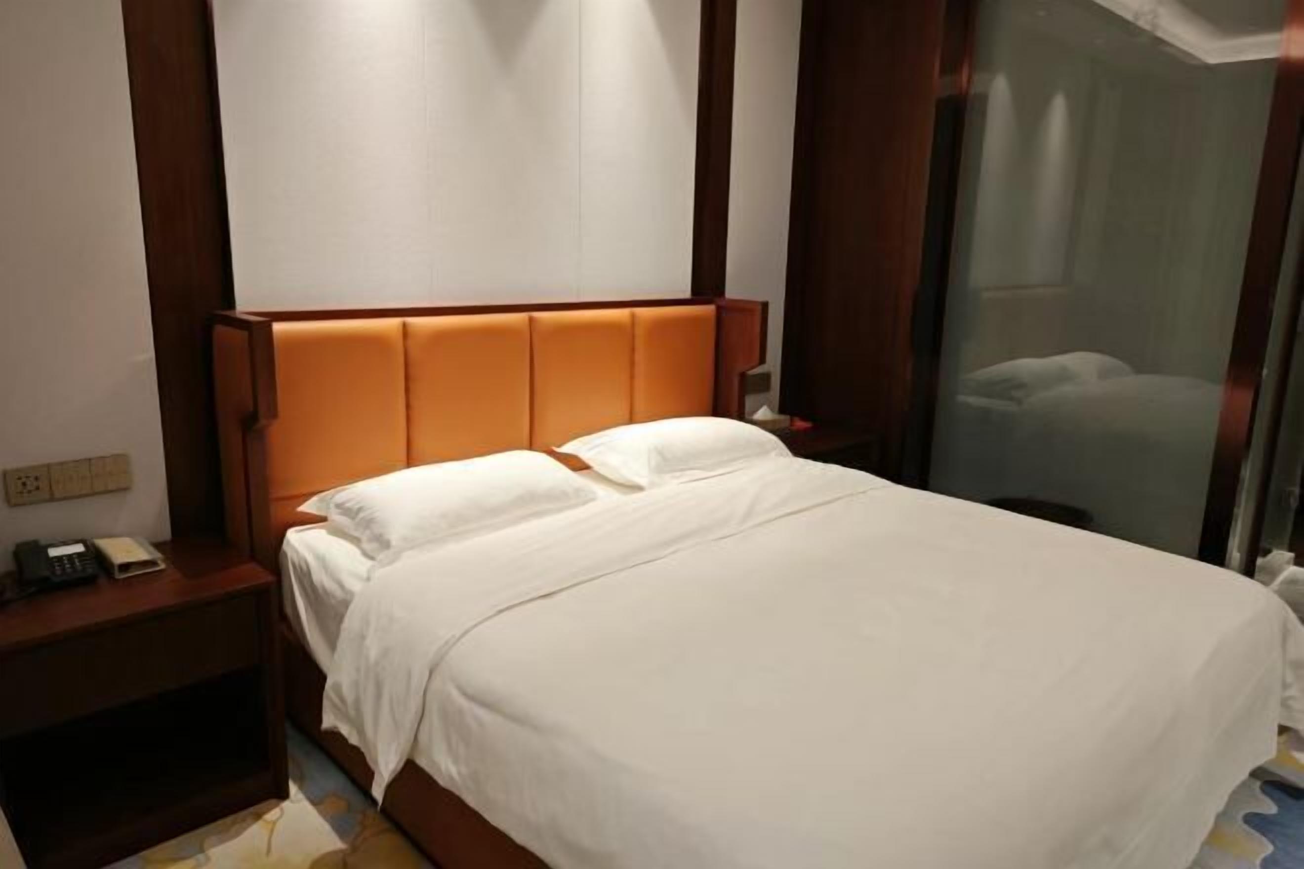 A hotel room with a bed, a nightstand, and a telephone.