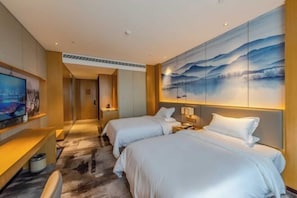 A hotel room with two beds, a TV, and a large painting on the wall.