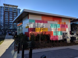 Ein modernes Gebäude mit farbenfroher Fassade, einem sichtbaren Schild mit der Aufschrift "CREAMERS" und blauem Himmel.