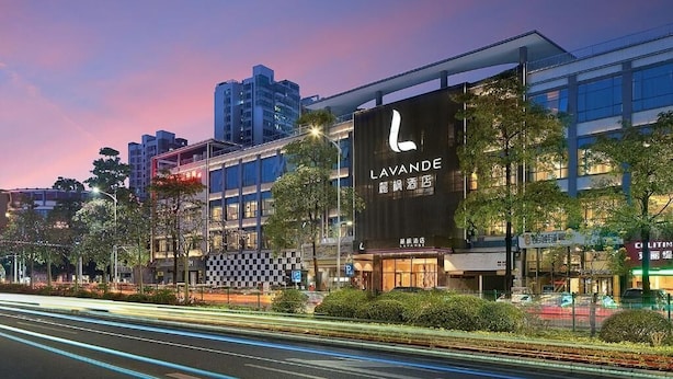 A modern hotel with a prominent sign, surrounded by urban buildings and a well-lit street at dusk. - Lavande Hotel(Guangzhou Baiyun Airport Shuguang Road) (Guangzhou)