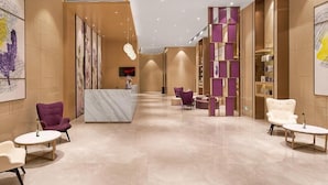 A hotel lobby with a reception desk, seating areas, and a decorative wall. - Lavande Hotel(Guangzhou Baiyun Airport Shuguang Road) (Guangzhou)